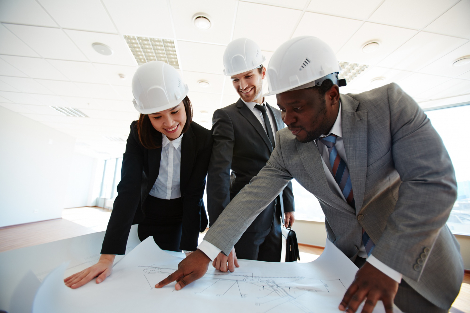 Professionals in hard hats reviewing architectural plans